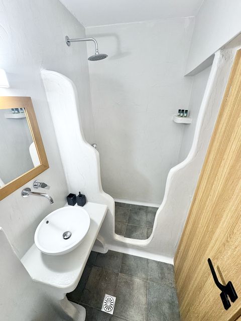 Curved walk-in shower with rain shower head and grey stone floor
