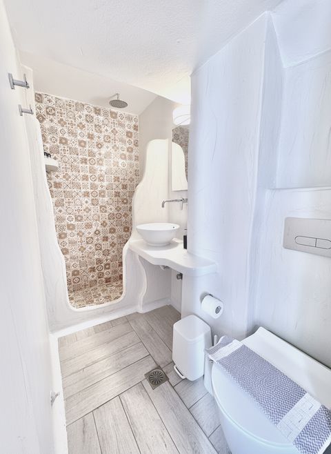 Walk-in shower with patterned tiles beside a vessel basin and wall-hung toilet